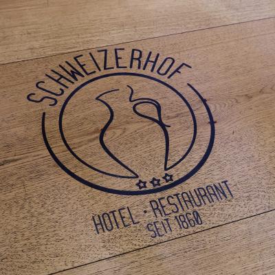 In Holz gebranntes Logo des Gasthof Schweizerhof