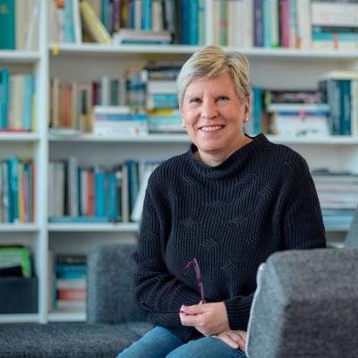 Ursula Miola auf einem Sessel vor einem Bücherregal